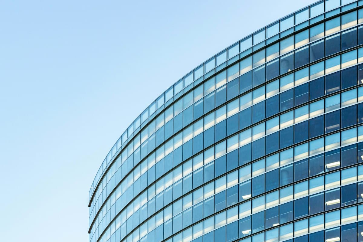 Curved glass facade of a modern office building against a blue sky